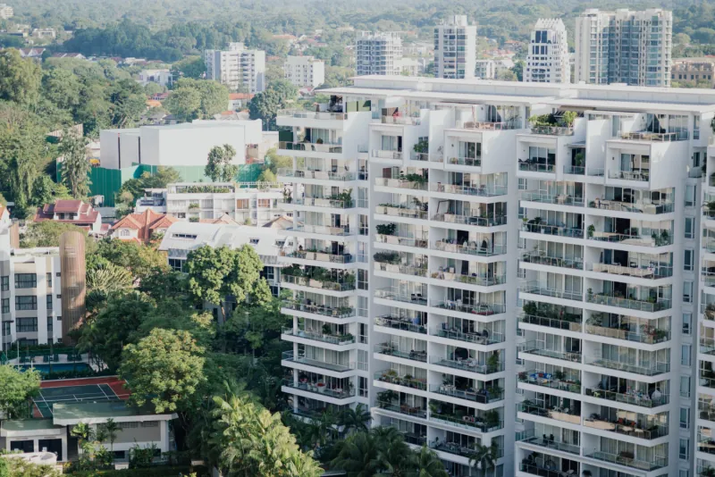Exterior of a multi story apartment complex with planted balconies overlooking a green neighborhood