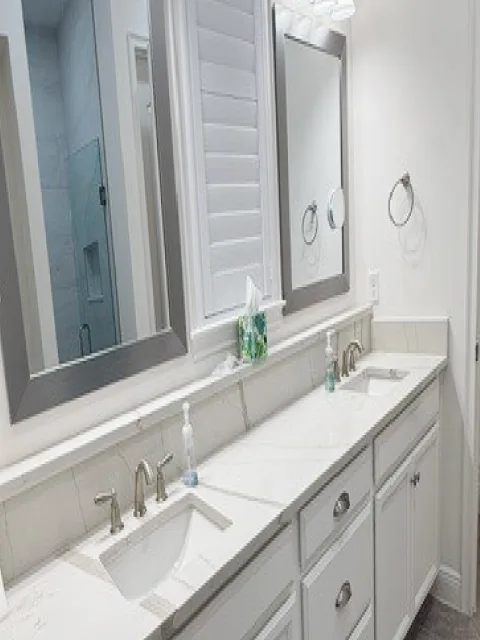 Bathroom renovation with a double vanity, framed mirrors and large format tile floor