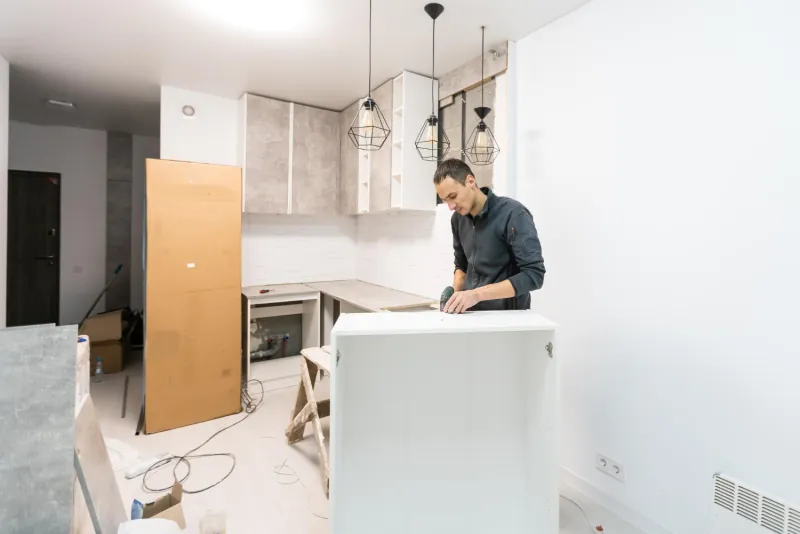 Installer fitting the countertop on a new kitchen island in a room still under renovation