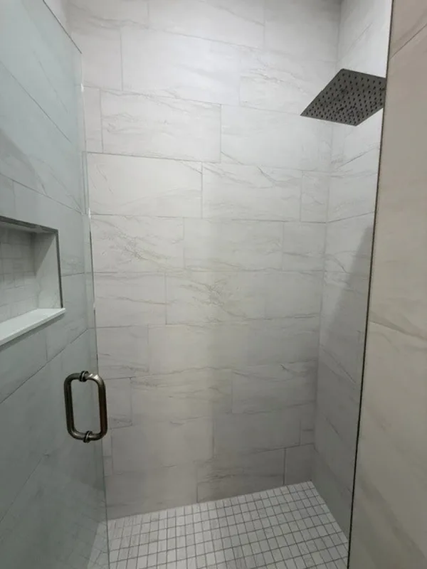 Lake Nona primary bathroom after renovation, with a walk in tile shower and glass enclosure