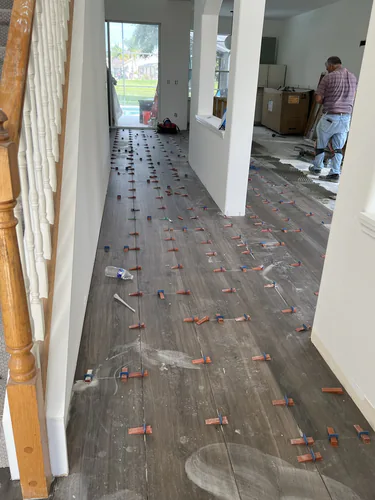 Plank flooring being laid along a hallway with spacers holding the expansion gap at every seam