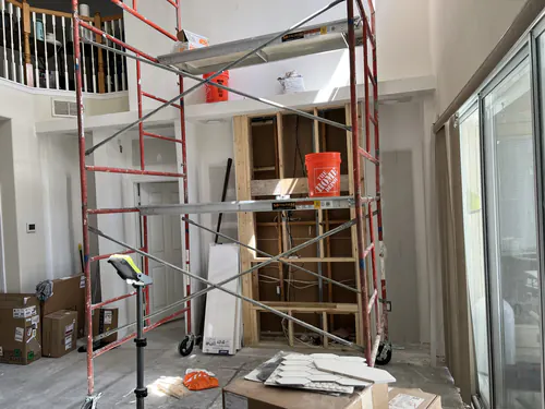 Rolling scaffold tower set up in a two story room so the crew can reach the ceiling and upper drywall