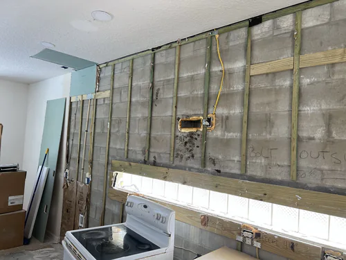 Concrete block wall furred out with treated timber strips, new cable run to an outlet box, moisture resistant drywall waiting to go up
