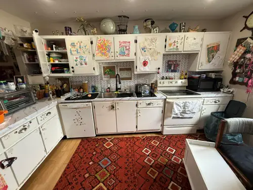 The kitchen before work started, with original painted cabinets, laminate counters and white appliances