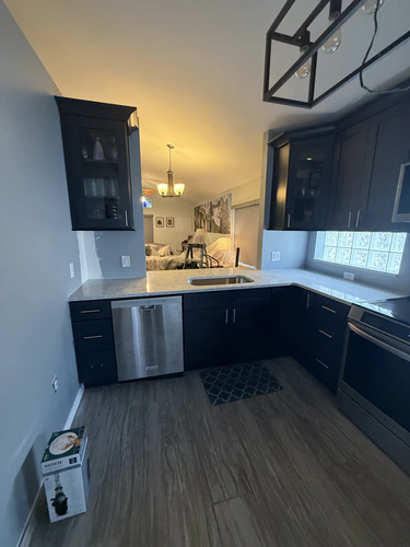 Finished sink wall with a wide square opening looking through to the living room and dining chandelier