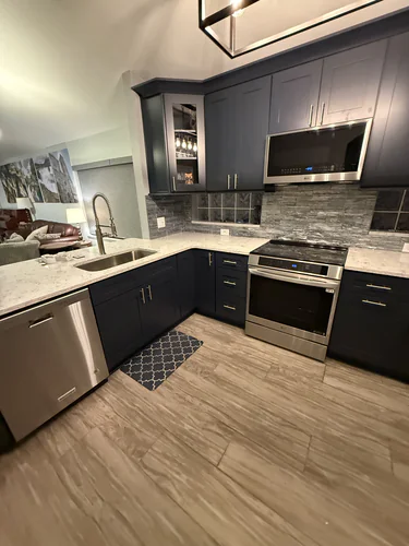 Renovated Orlando kitchen with navy shaker cabinets, light countertops, a grey stacked stone backsplash and a stainless range