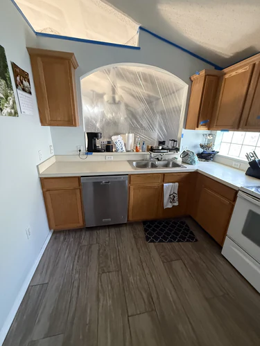 Original sink wall with an arched pass through above the sink, sealed with plastic sheeting from the living room side
