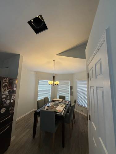 Dining room with the popcorn removed and the ceiling finished flat, with two grey paint samples brushed on the wall