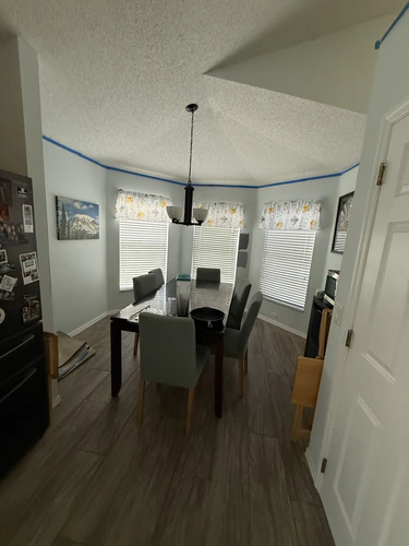 Dining room with a popcorn ceiling and blue painter's tape along the top of the walls