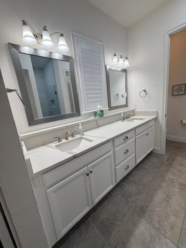 Finished Ocoee primary bathroom with a double vanity, framed mirrors and grey floor tile