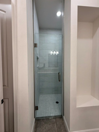 Finished Ocoee walk in shower seen through its frameless glass door, tiled in large format marble look tile