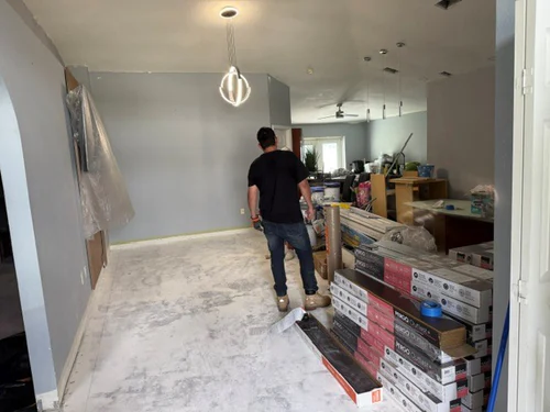 Room stripped back to bare slab with freshly painted grey walls and boxes of plank flooring stacked ready to lay